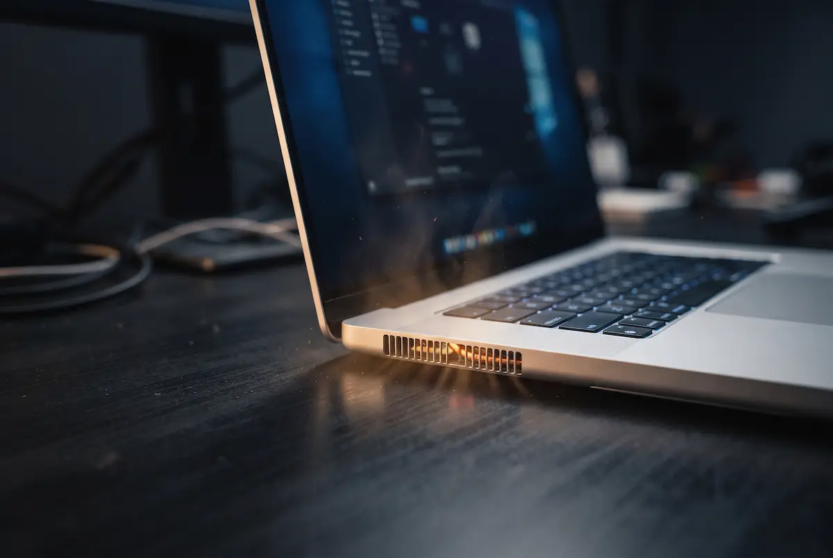 Silver laptop on a desk with warm air coming from the rear vents